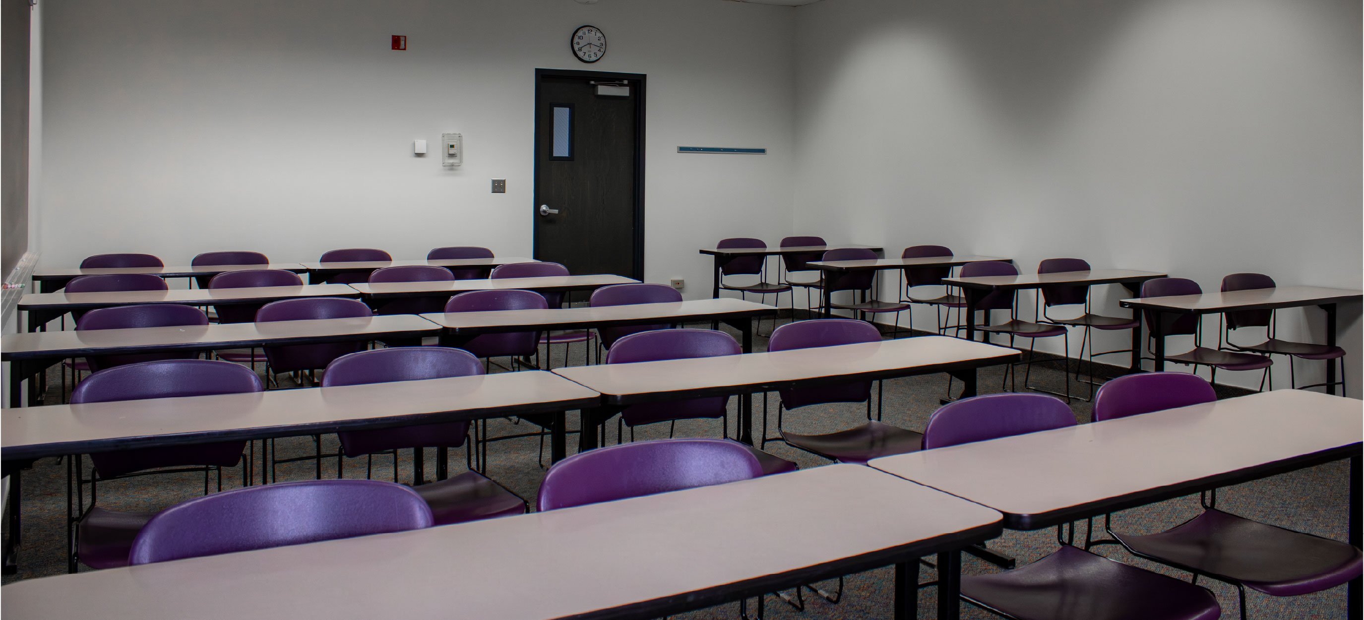 CHE classroom with rows of tables and purple chairs arranged in a traditional classroom layout.