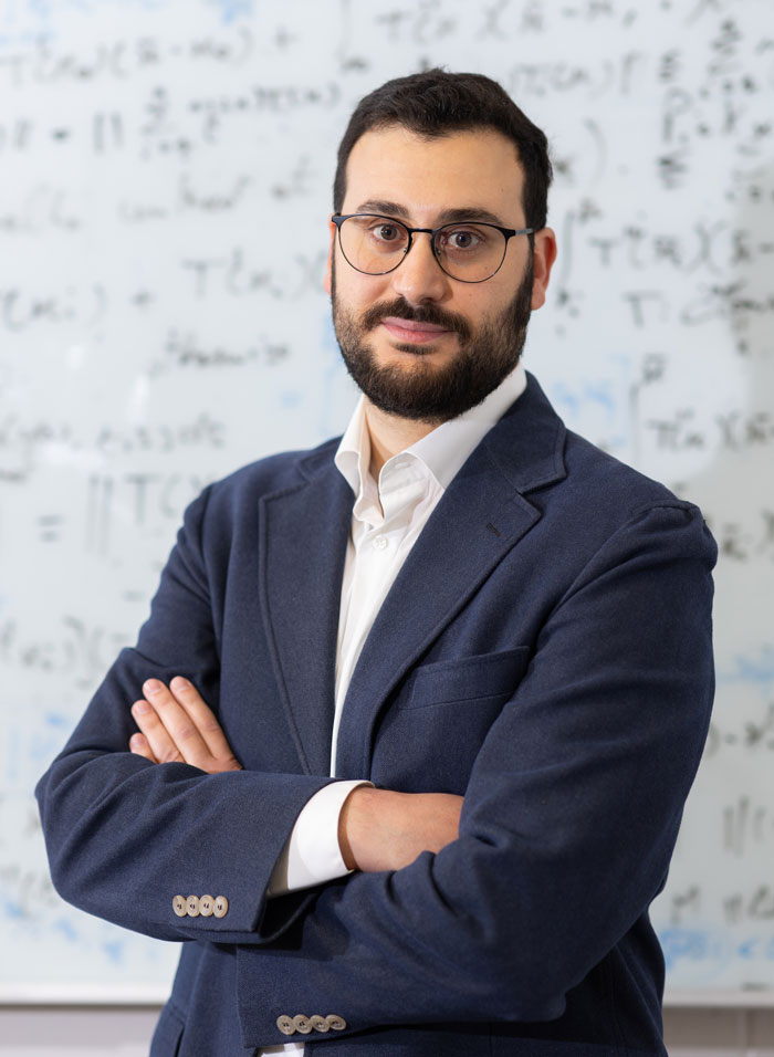 Emanuele Zappala in front of a white board with mathematical equations