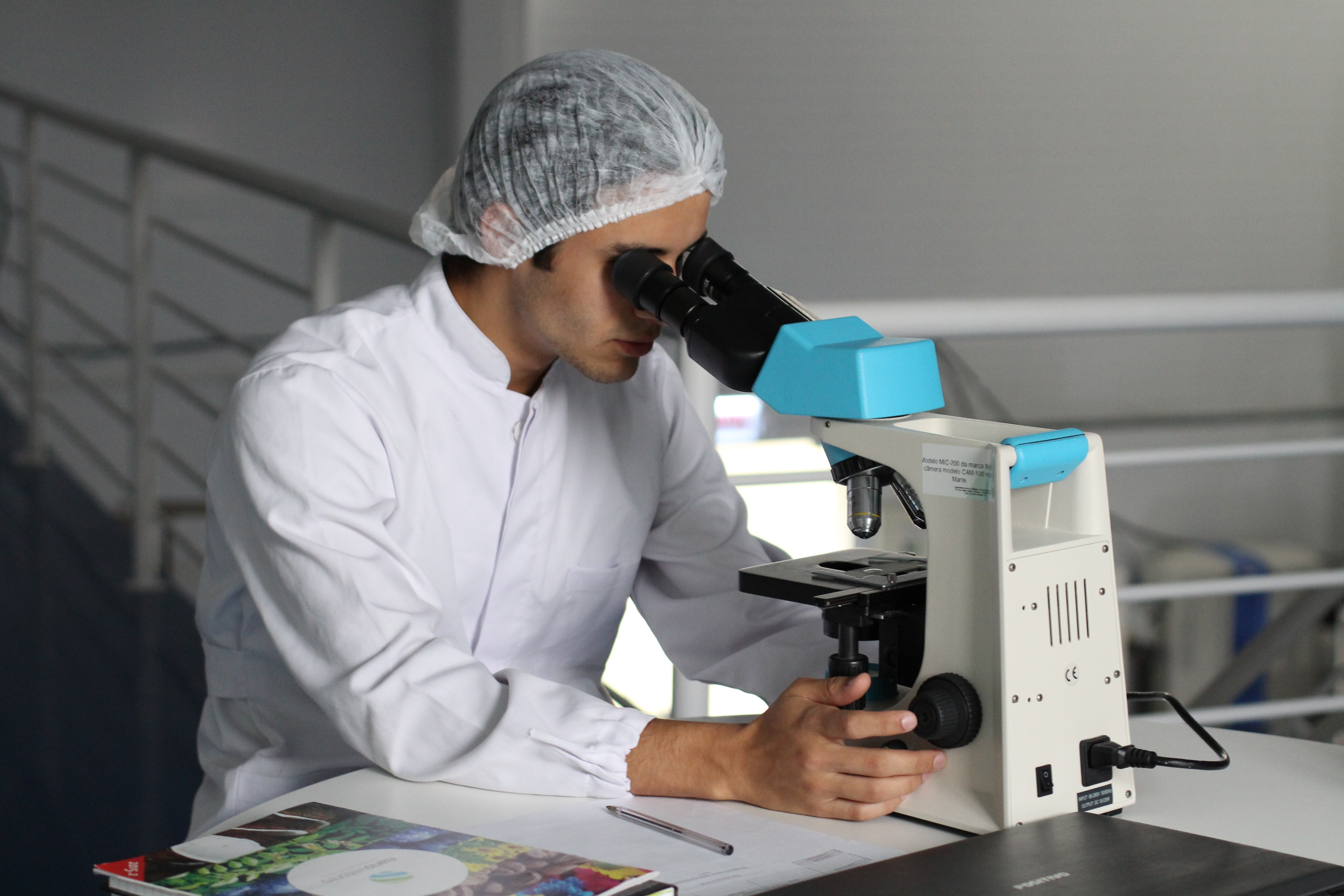 A student sitting and looking through a microscope.