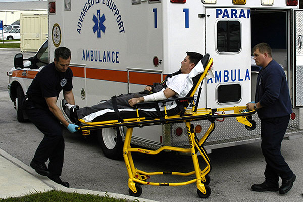 EMTs with patient on a stretcher in front of an ambulance