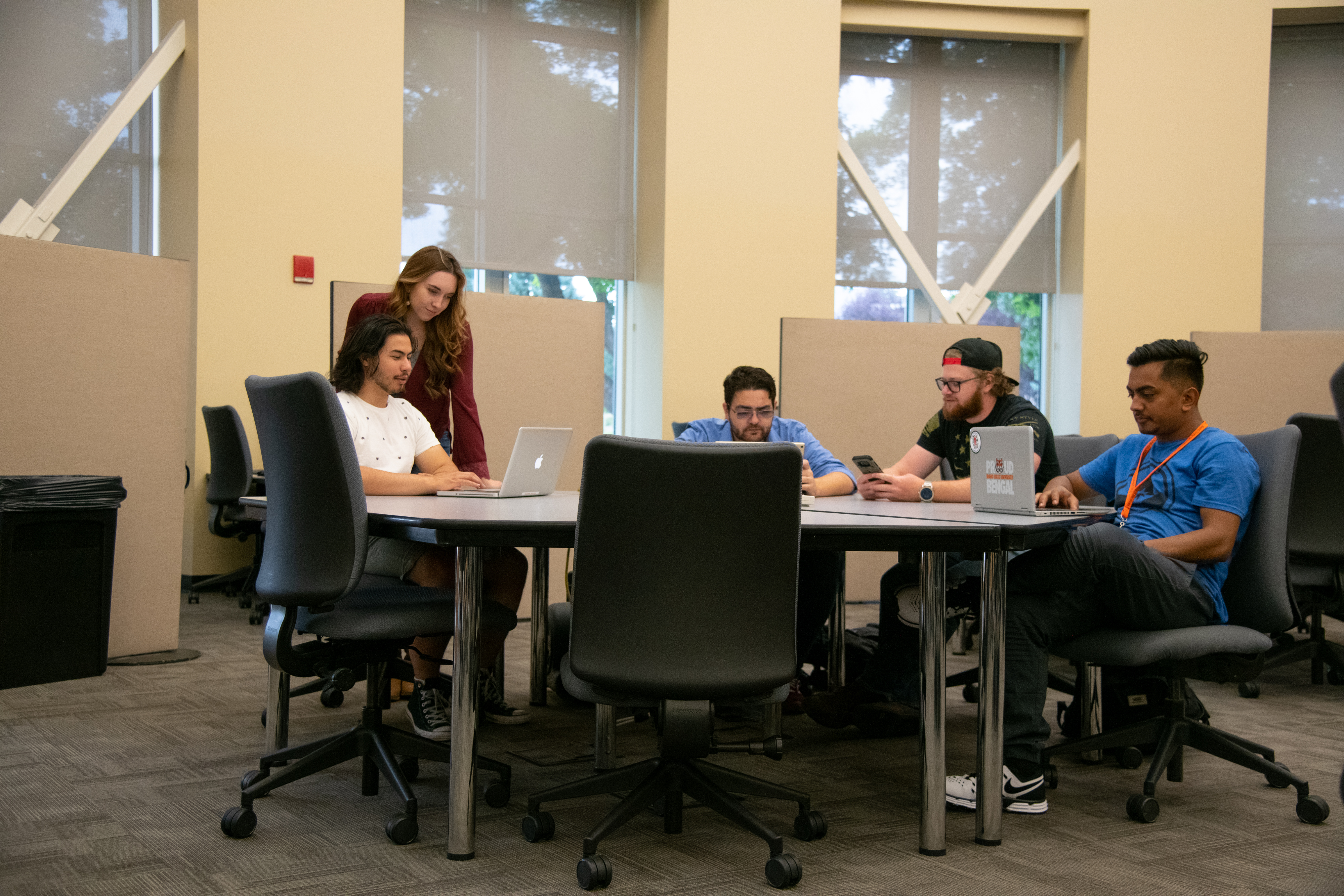 A group of students sitting around a table in a computer lab.