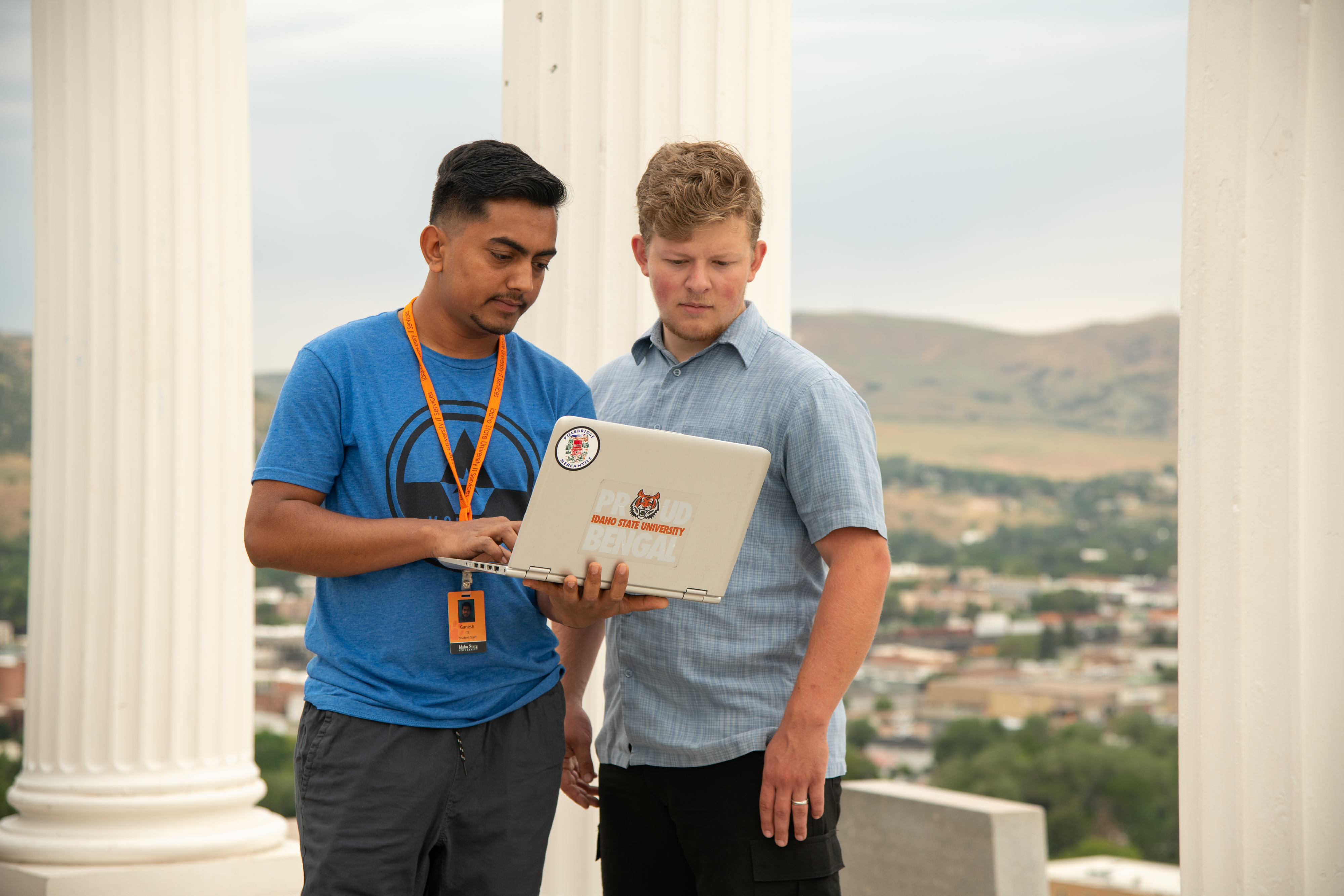 Two students under the pillars on Red Hill looking at a laptop.