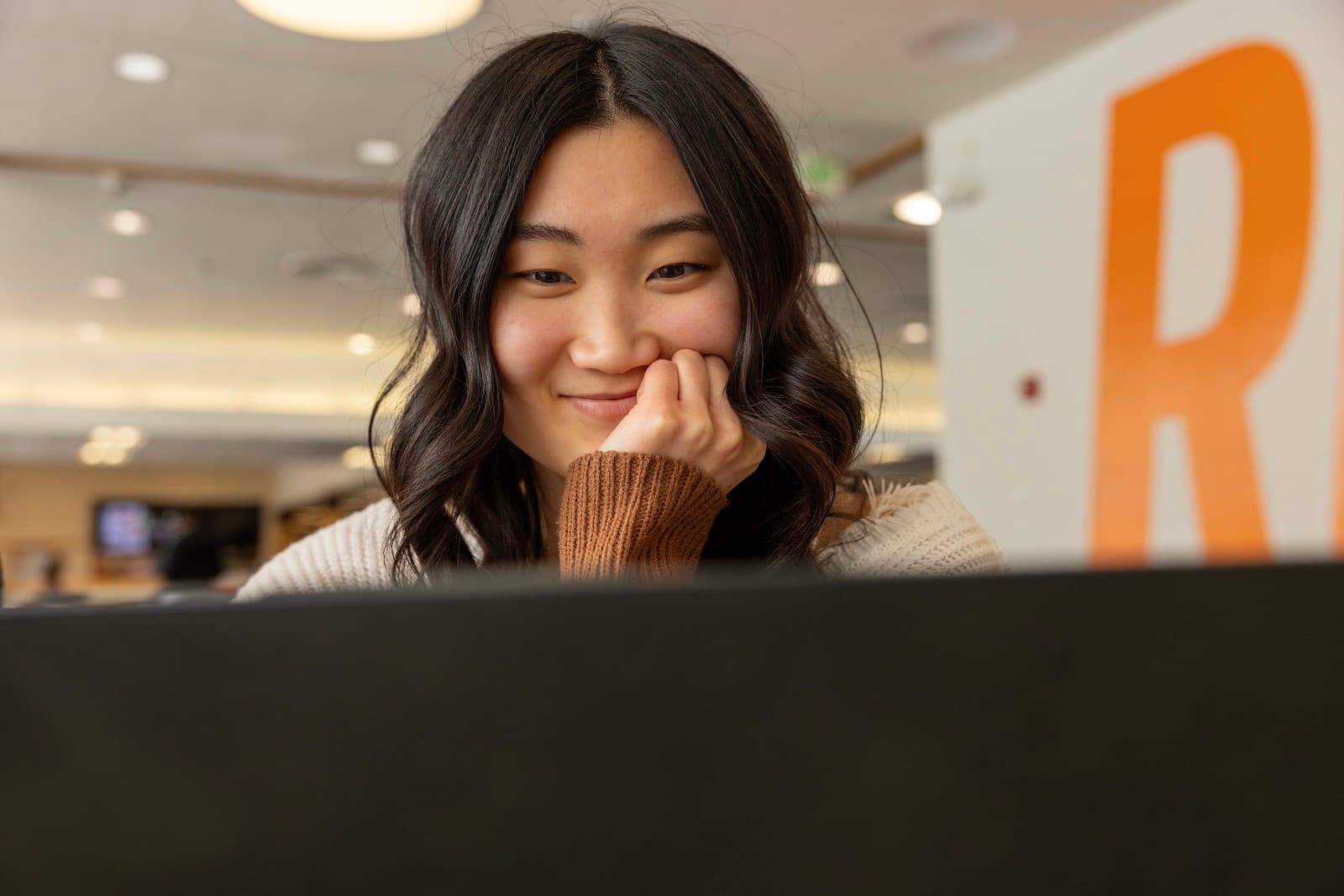 A woman smiles while looking at a computer screen