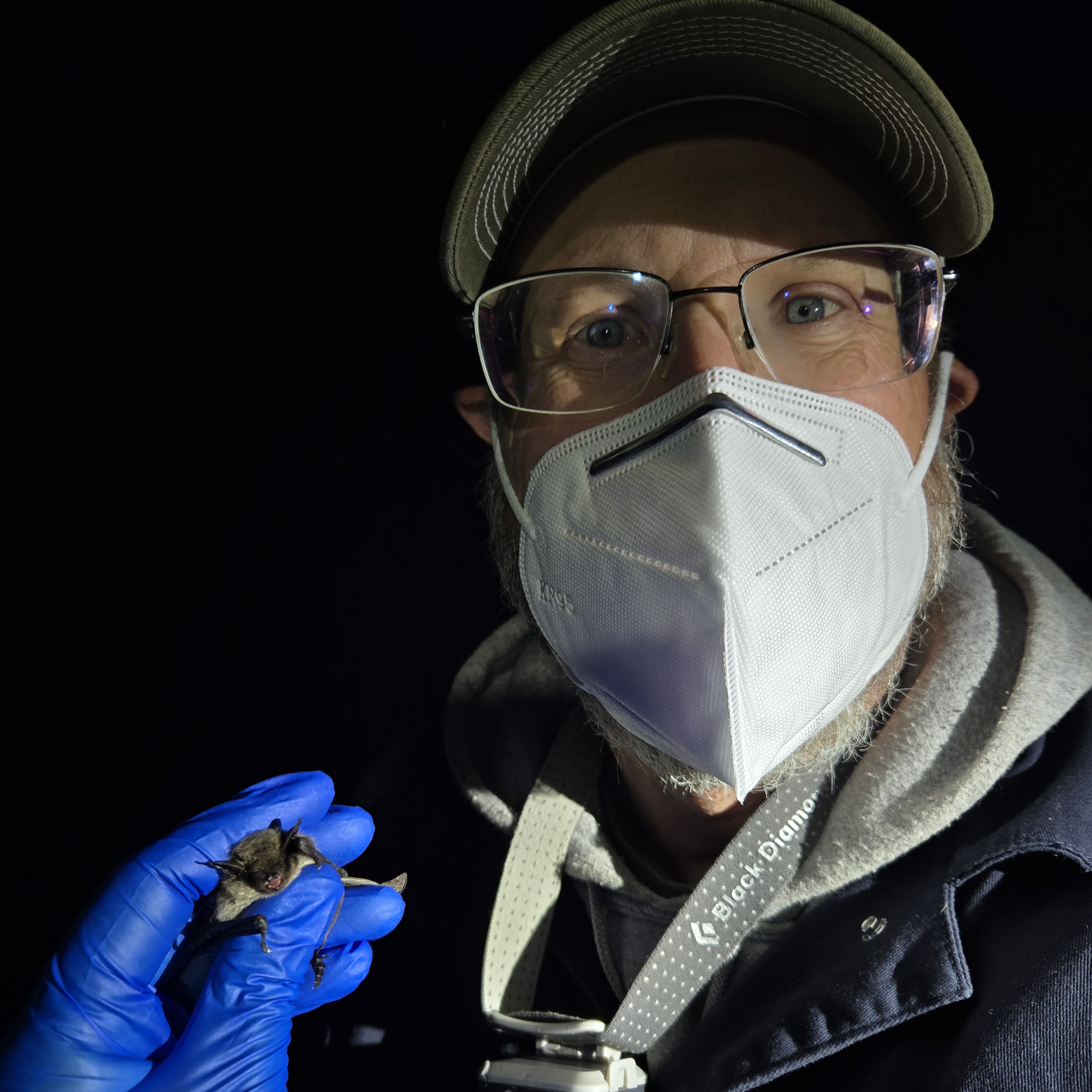 Man with mask holding a bat in the dark