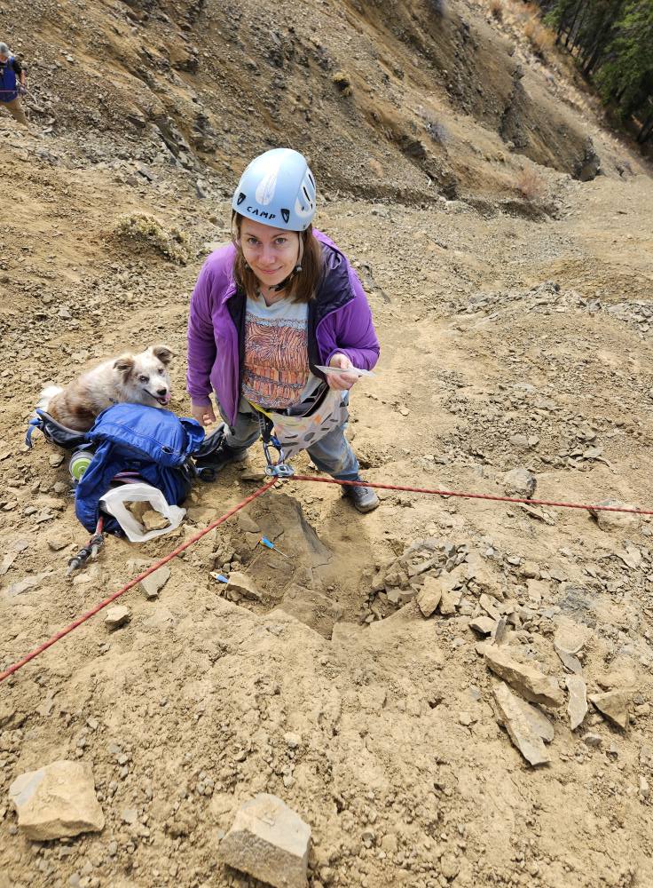 Meaghan Wetherell working in the field along side her white and yellow dog