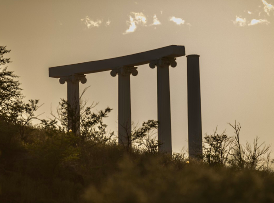 3 connect pillars with one unconnected pillar on a hill at dusk