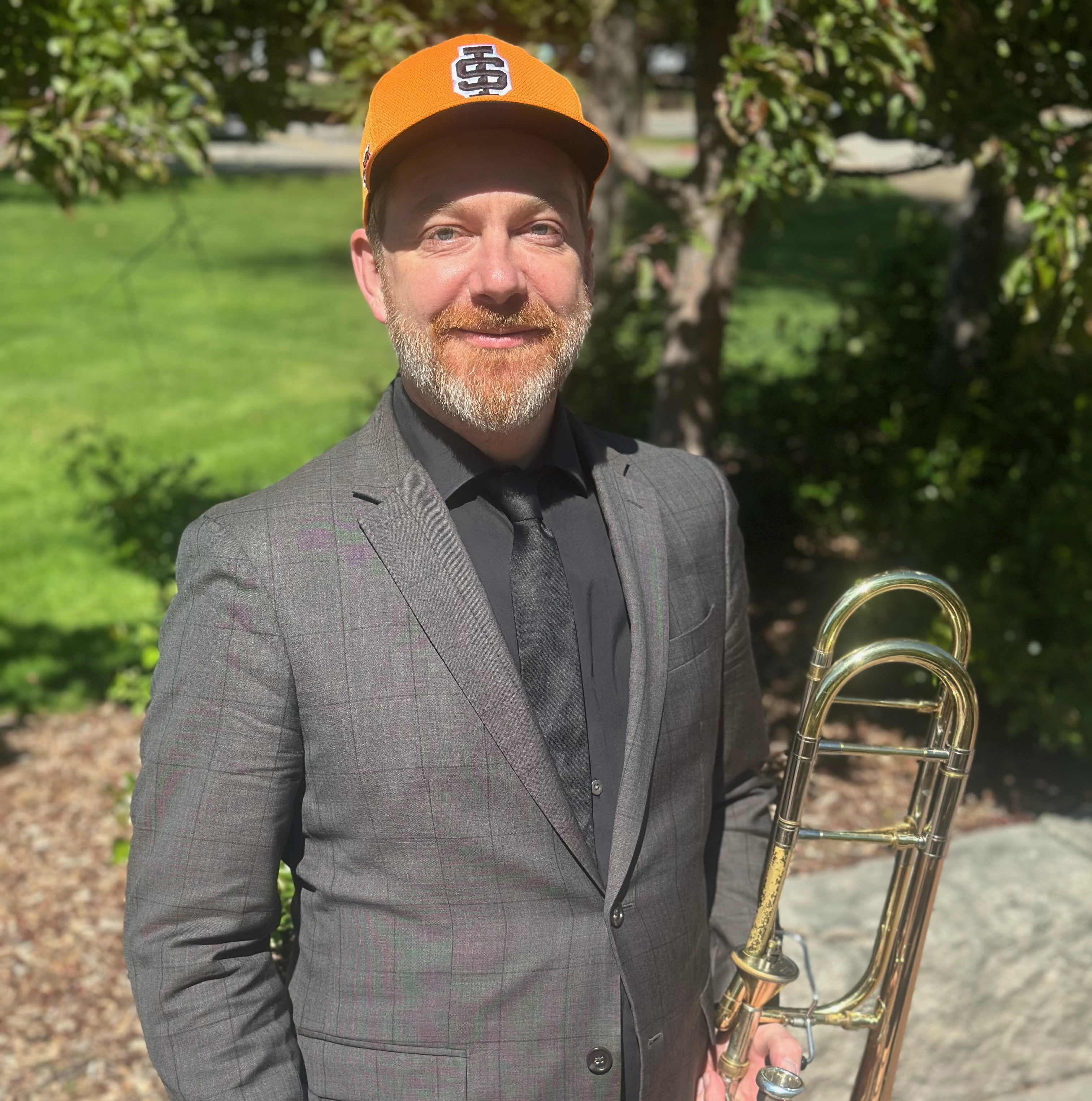 Dr. Luke Strother with his trombone and wearing a classy ISU hat