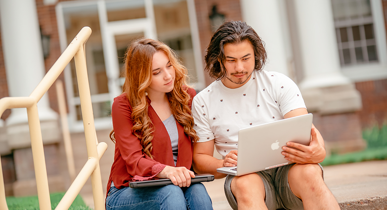 Two students looking at a laptop