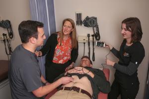 PA students giving ultrasound on a patient with instructor guiding them