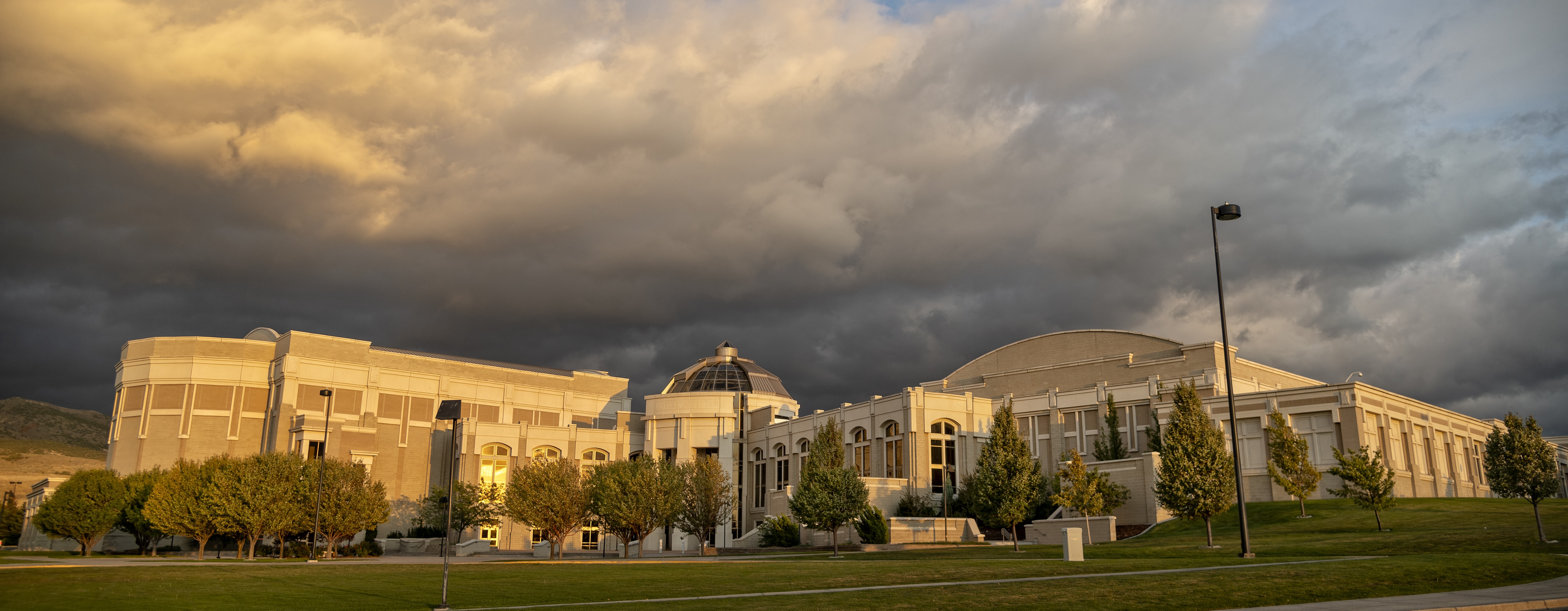 The sun setting on the Stephens Performing Arts Center with clouds blowing in overhead