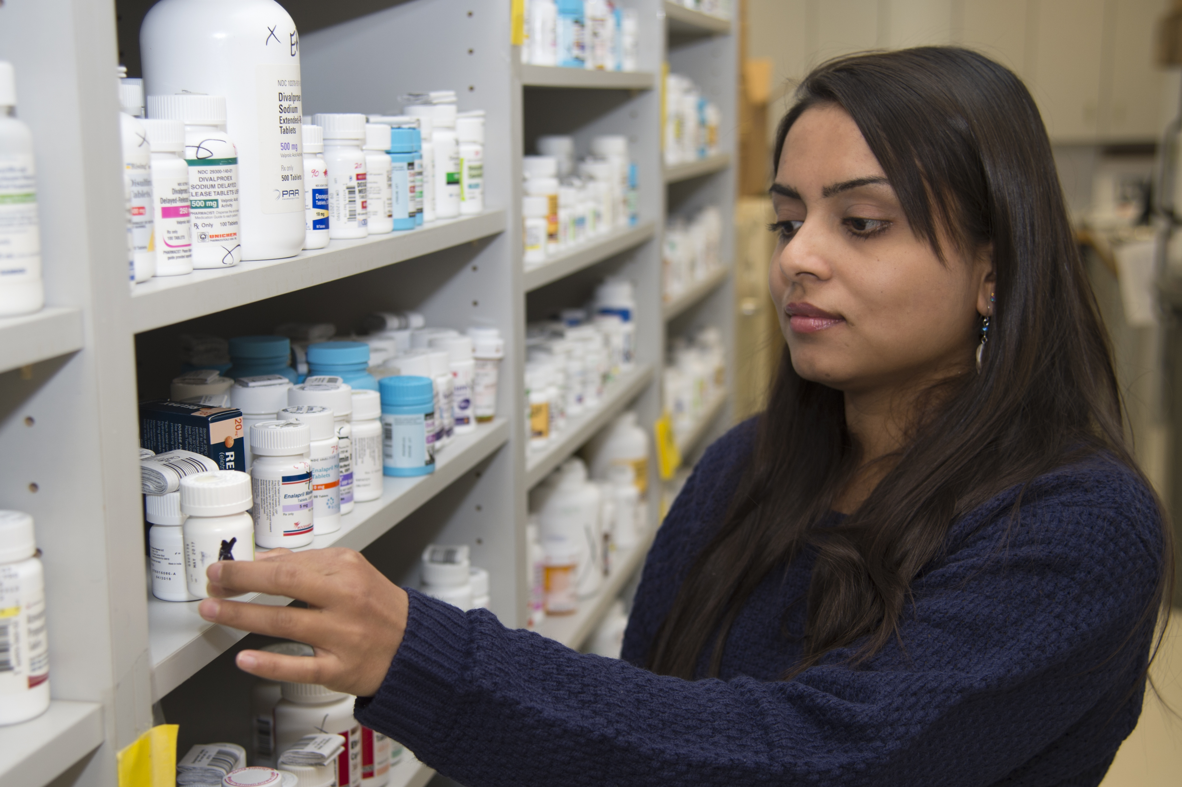 Female pharmacists places prescription bottle on shelf