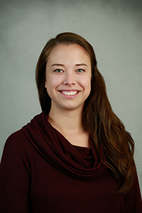 Aminda Skan professional headshot, smiling, in a dark red sweater