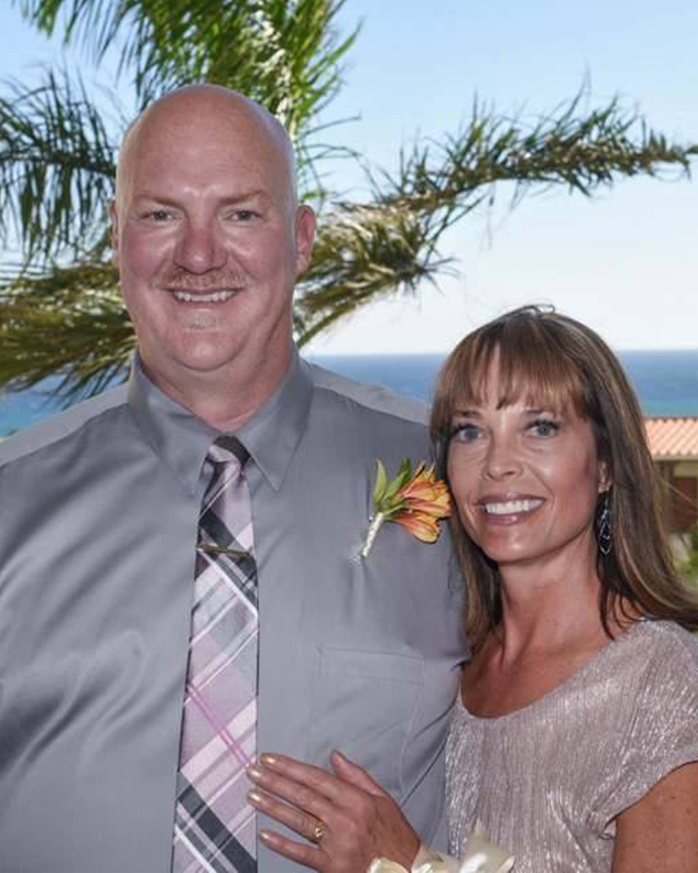 Dan & Barb Fuchs with a palm tree and ocean scene in the background