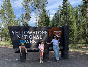 Suyeon Kwon poses in front of a sign at Yellowstone National Park