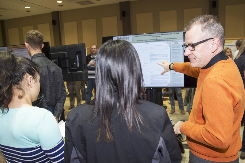 Bryan Gee, Chair/Associate Professor/Director of Occupational Therapy talks with ISU students during a poster presentation at Research Day 2017.