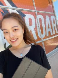 Suyeon Kwon poses in front of the word ROAR on a building at ISU in Pocatello