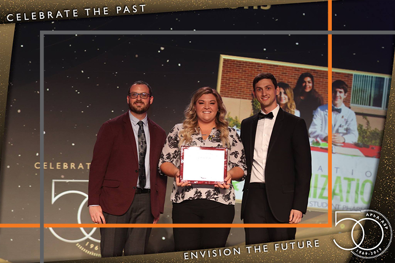 Student posing on stage at APhA-ASP 2019 awards ceremony with award plaque