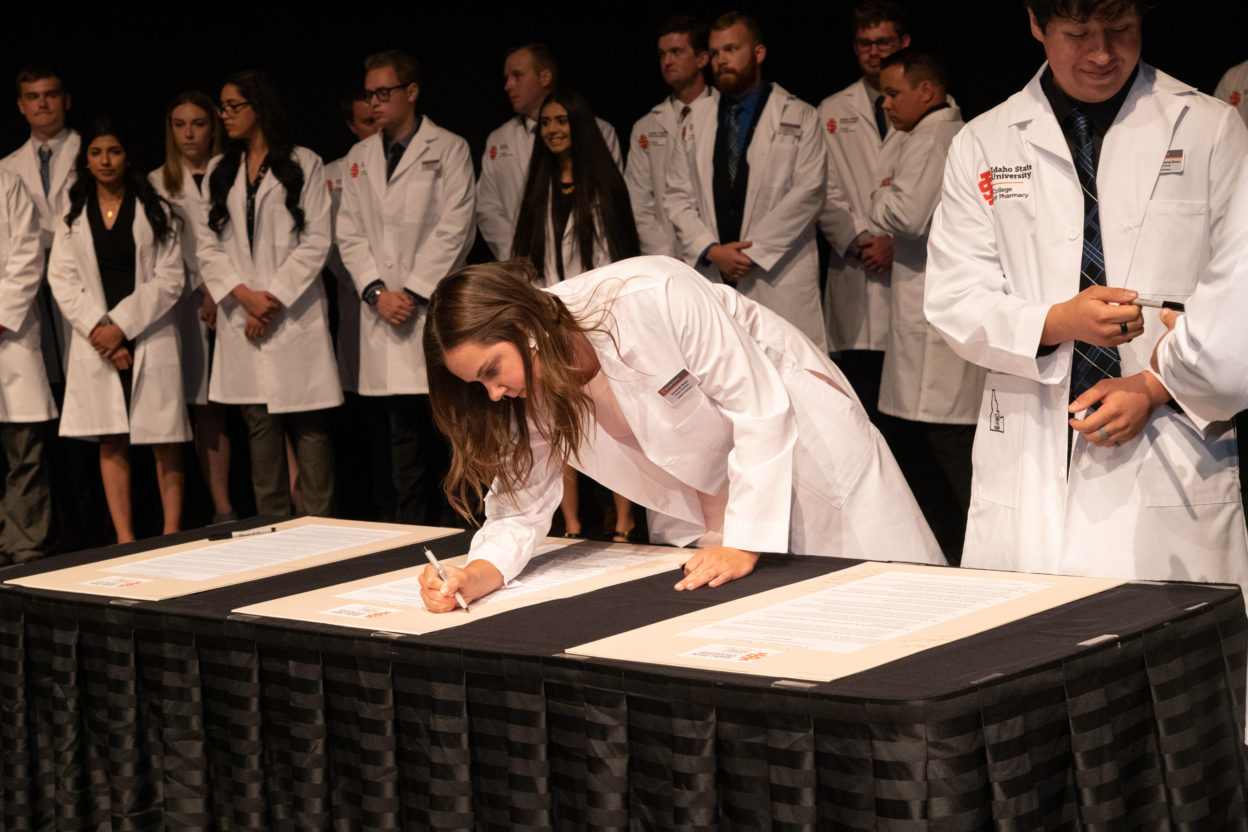 Students in white coats sign pharmacy Code of Ethics at 2019 ceremony