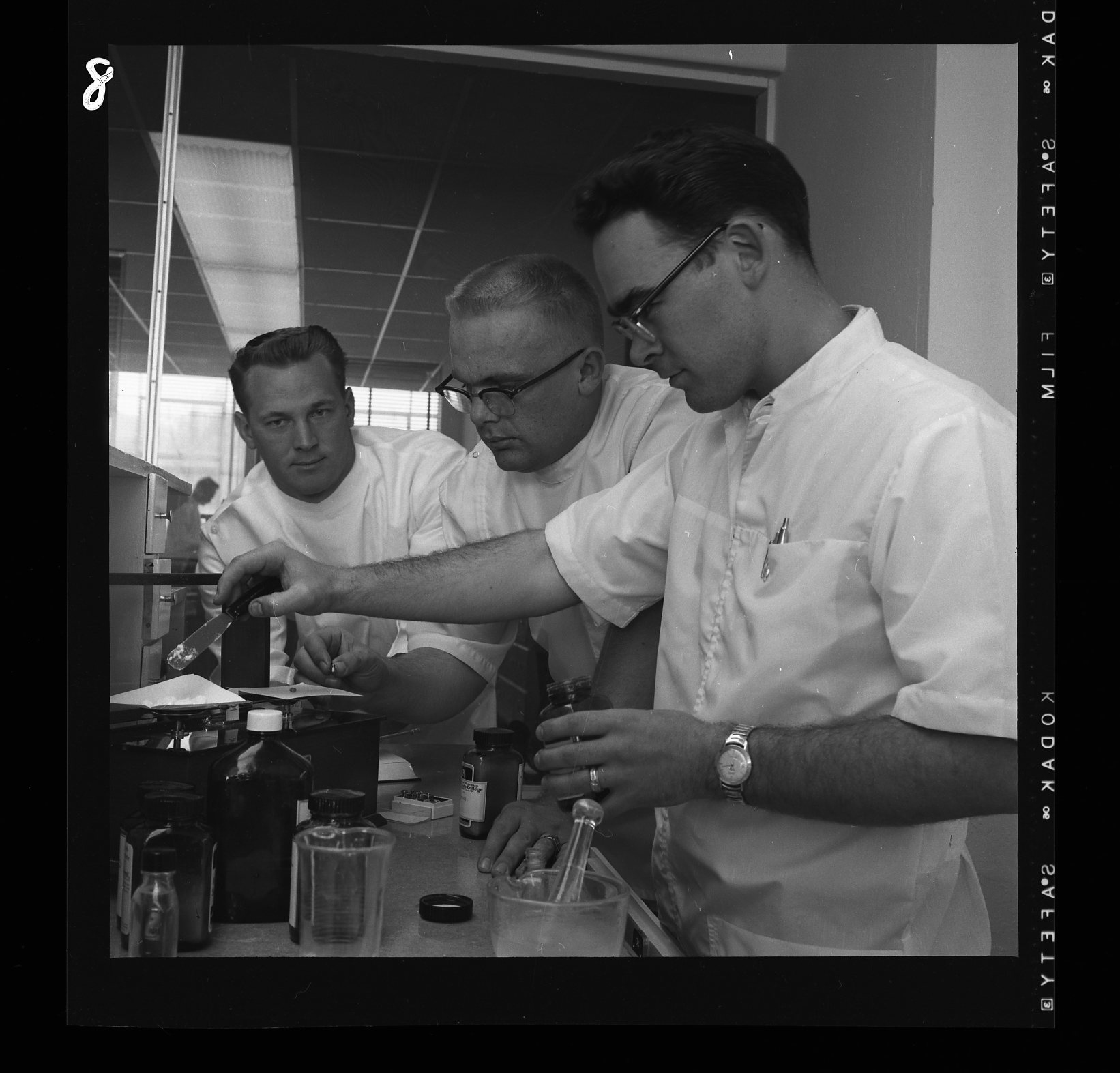 Pharmacists in lab coats prepare a compound