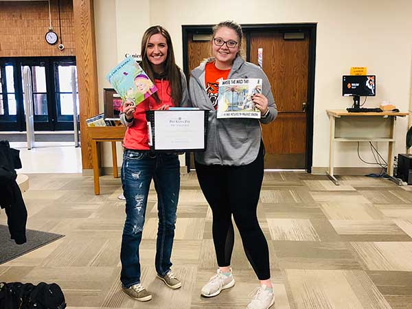 Vice presidents of PKP McKenzie Adams and Kylie Greenwell holding donated books.