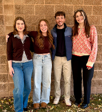 Four PsyD students standing outside brick building