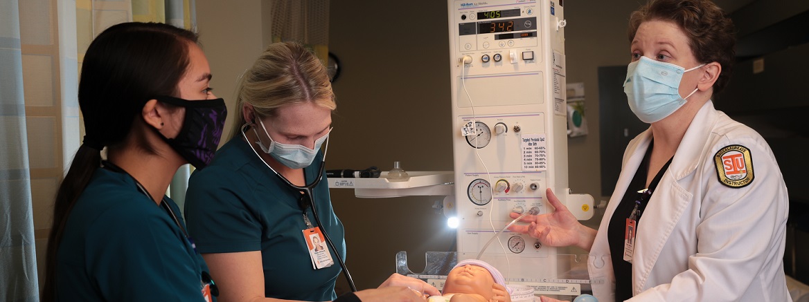 Students and instructor work on sim baby