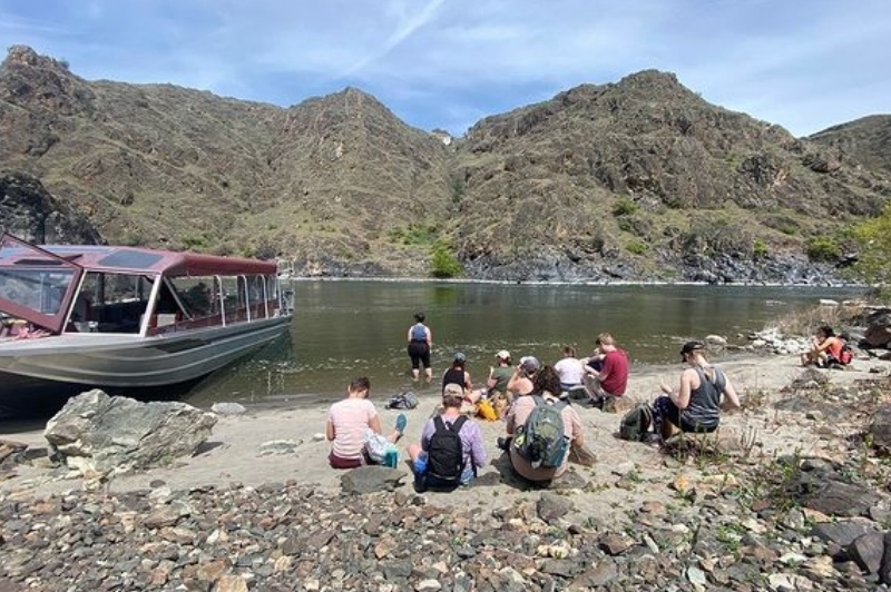 Adult learners eating together on rural Idaho beach after disembarking from their group boat trip.