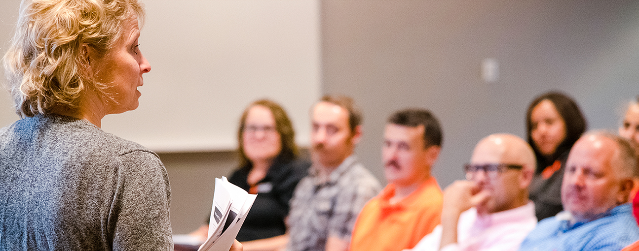 A group of staff members listening to the speaker at a meeting.