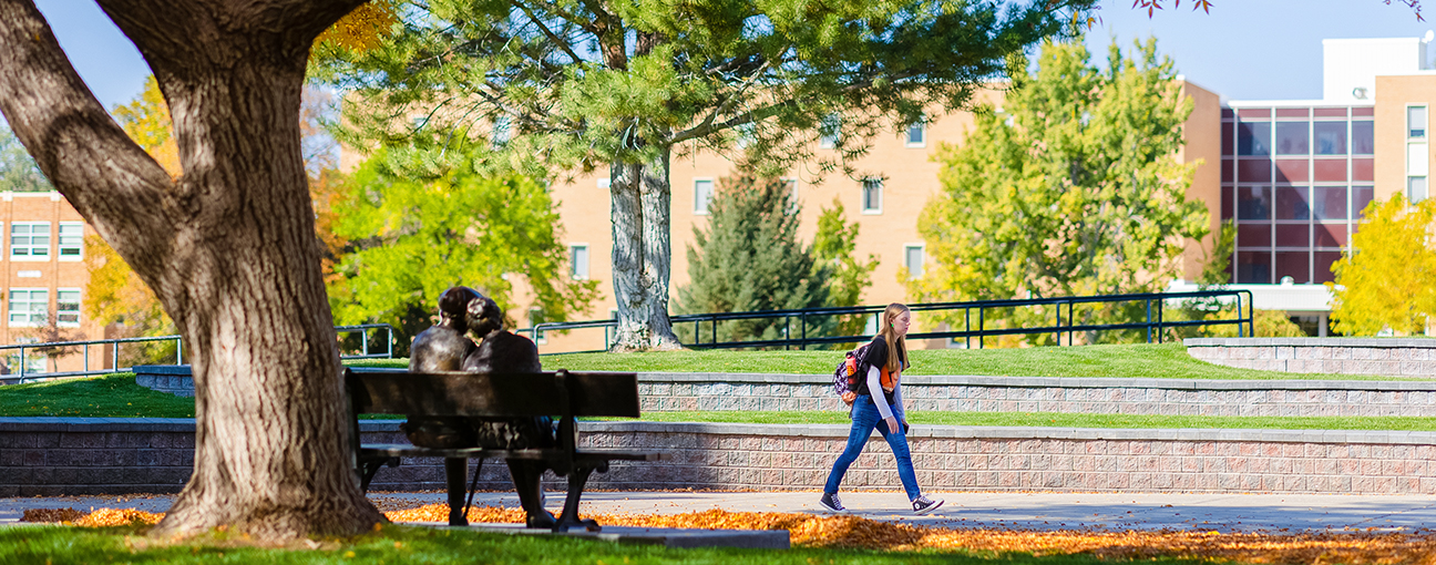 A student walking past the 'Valentine' bench sculpture