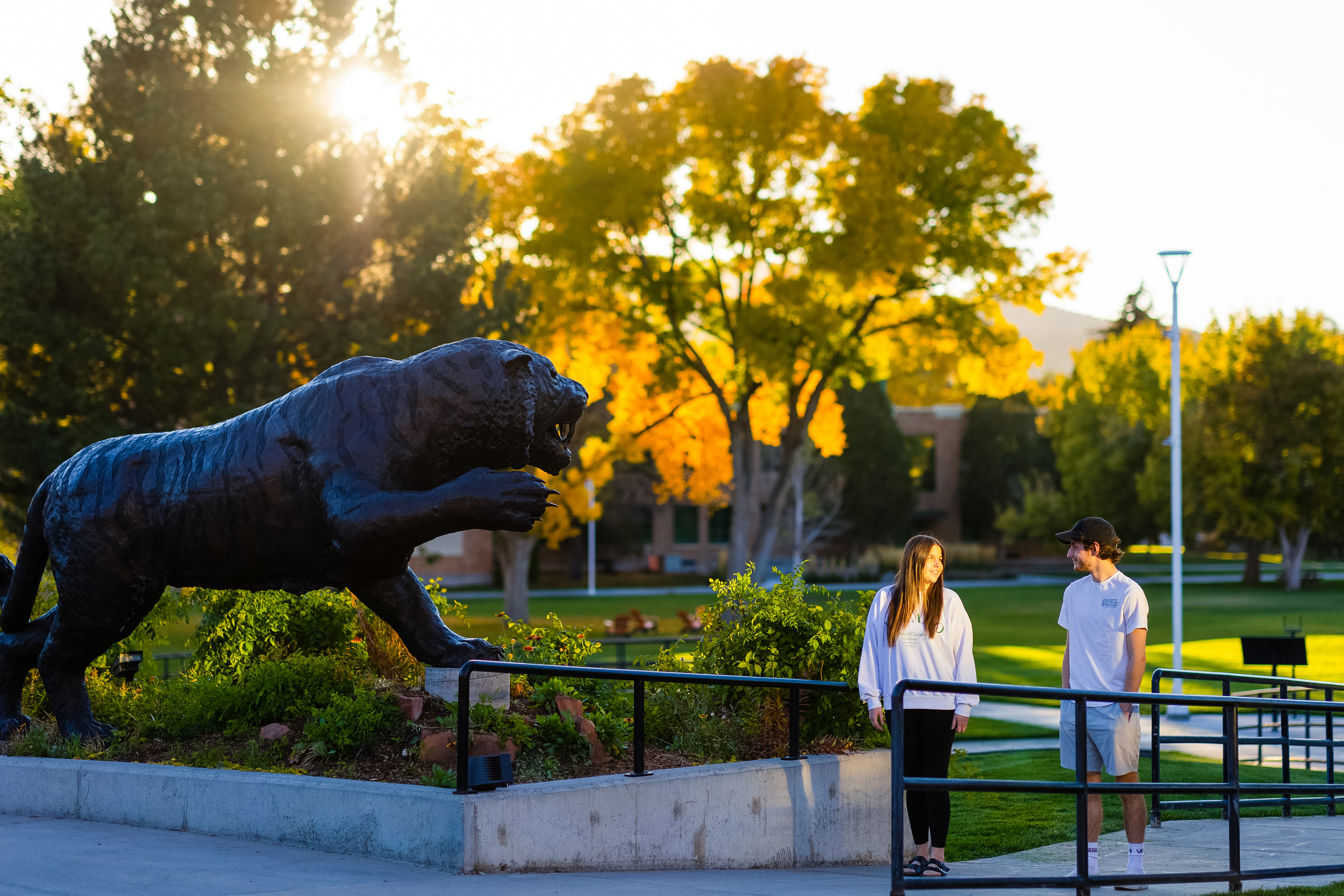 Two students walking next to the Bengal Tiger statue on the Quad.