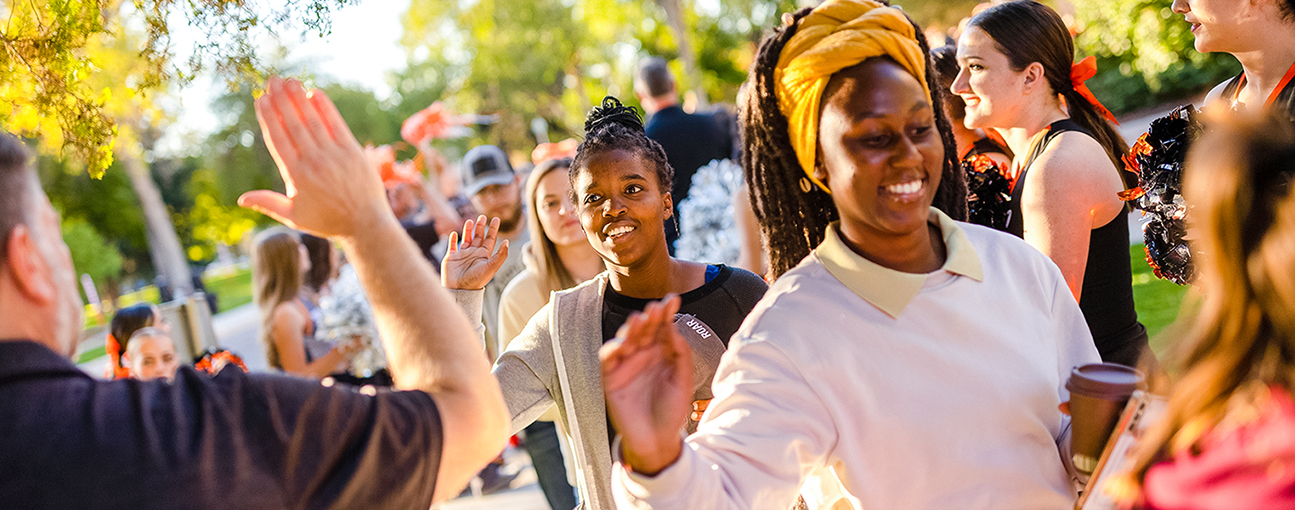 A group of students high-fiving a staff member