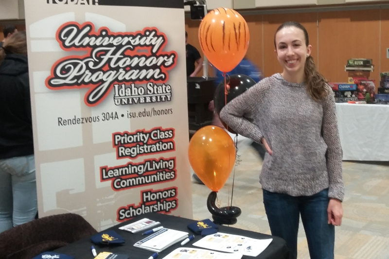 A student working at a booth for the Honors Program