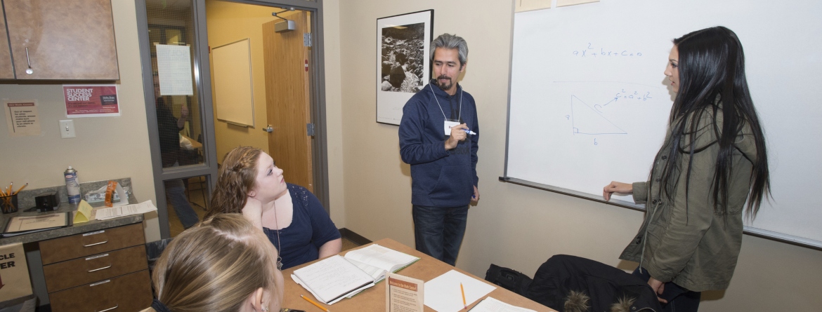 A tutor at a whiteboard talking to three students