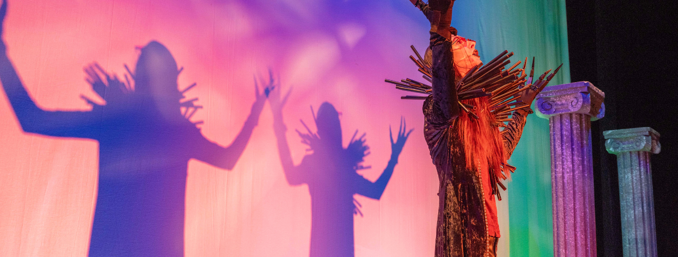 colorful pink and purple backdrop with actor in a gothic costume