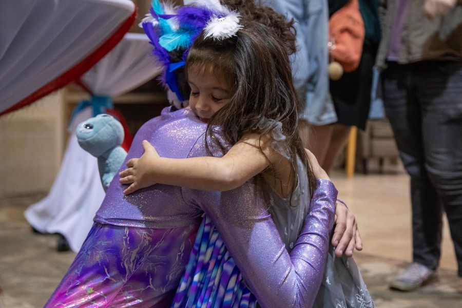 A cast member in costume hugs a small girl after a performance