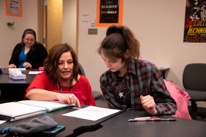 Teacher and Student sitting at a table with study materials.