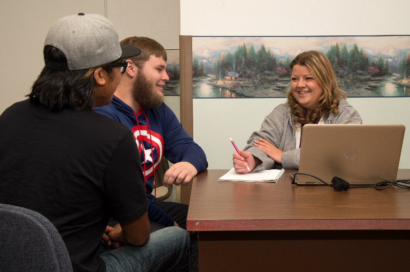 Three people having a meeting, sitting around a table.