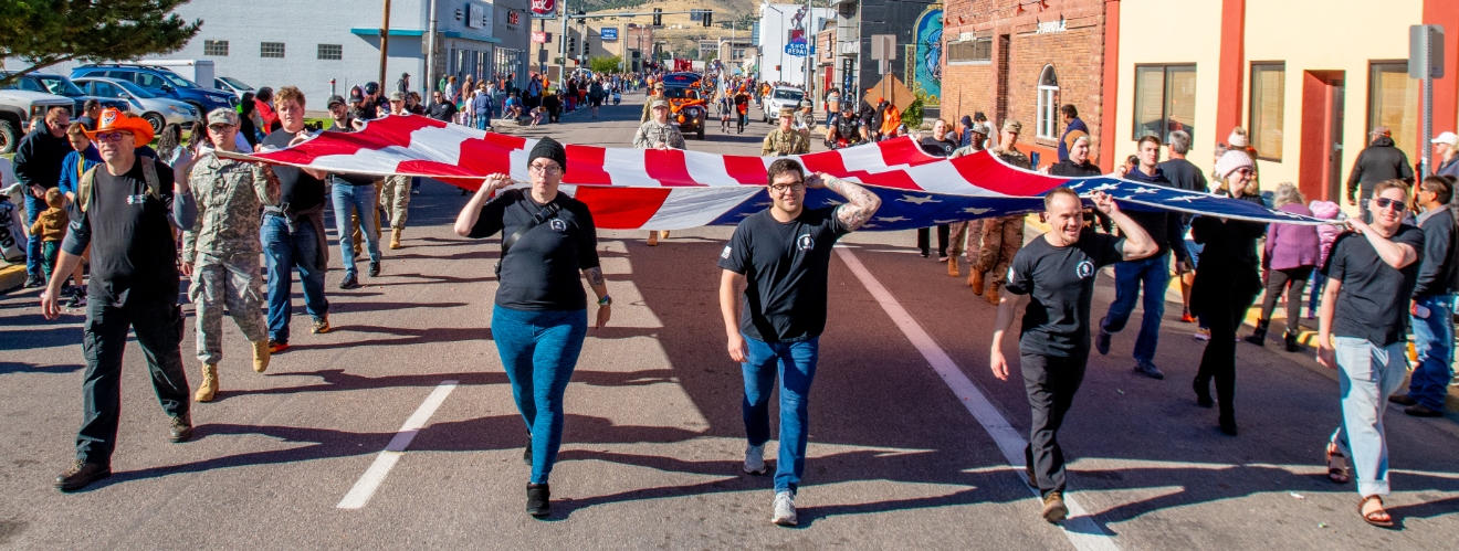 Students from the Veteran's Student Service Center and the TRiO Veterans Program walking the flag in the ISU Homecoming Parade 2023.