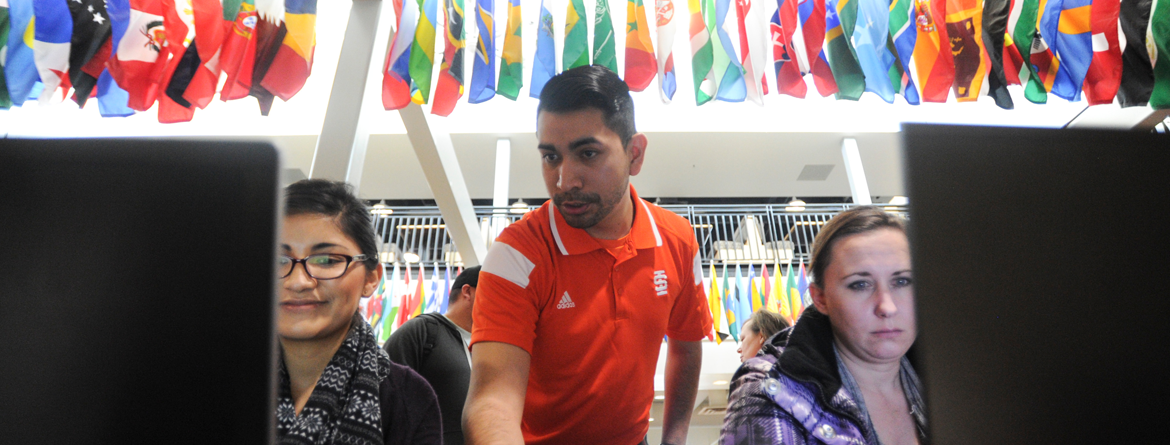 Students receiving registration help from ISU employee with international flags in the background