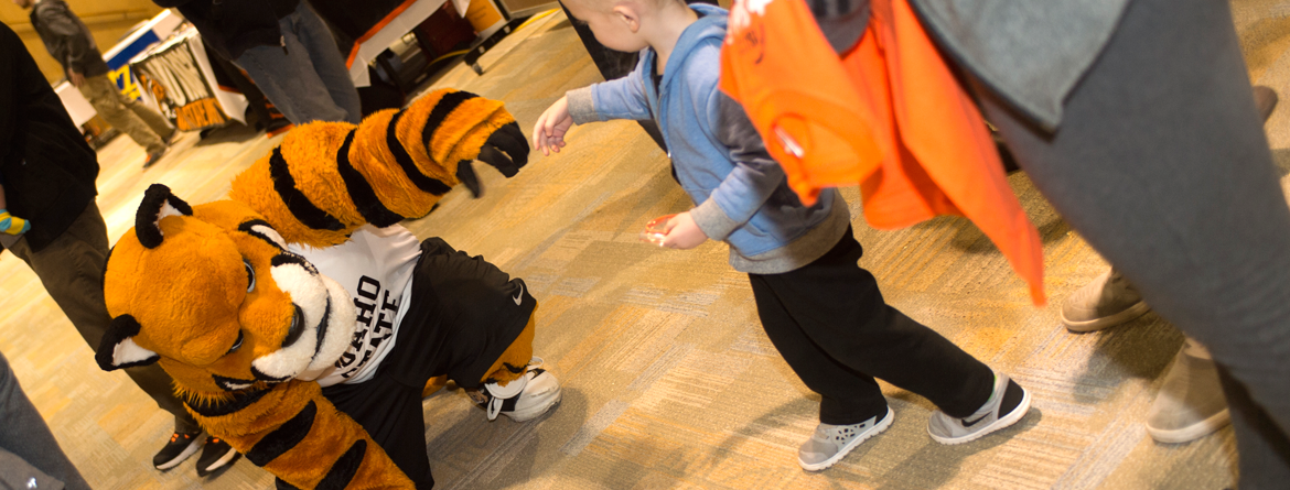 Benny the mascot benignly fist bumping child