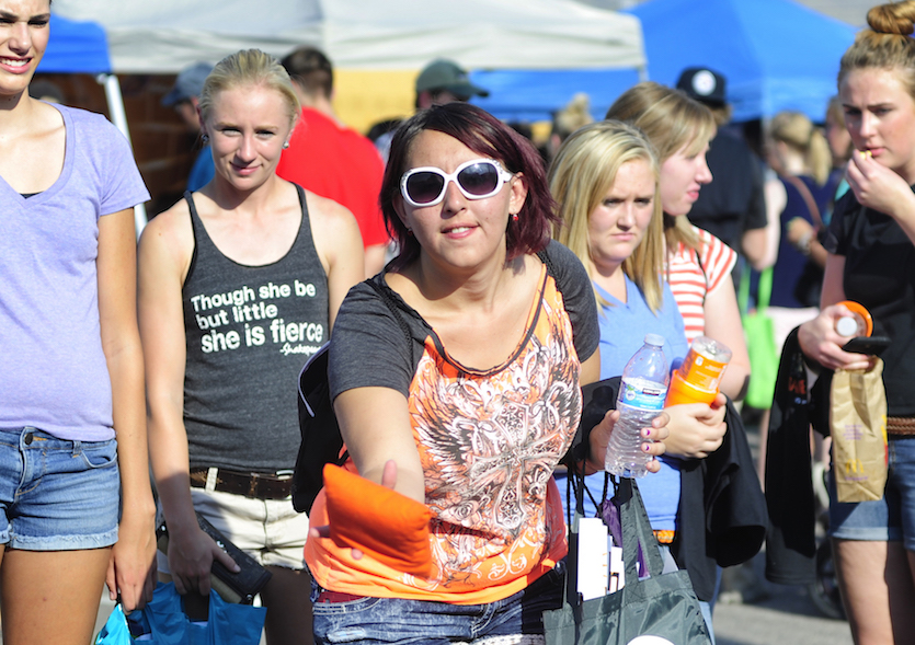 Student throwing a bean bag at a previous Welcome Back Orange and Black celebration. She is flanked by other students.