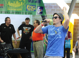 Image of a Welcome Back Orange Black participant talking in a microphone with others in the background.