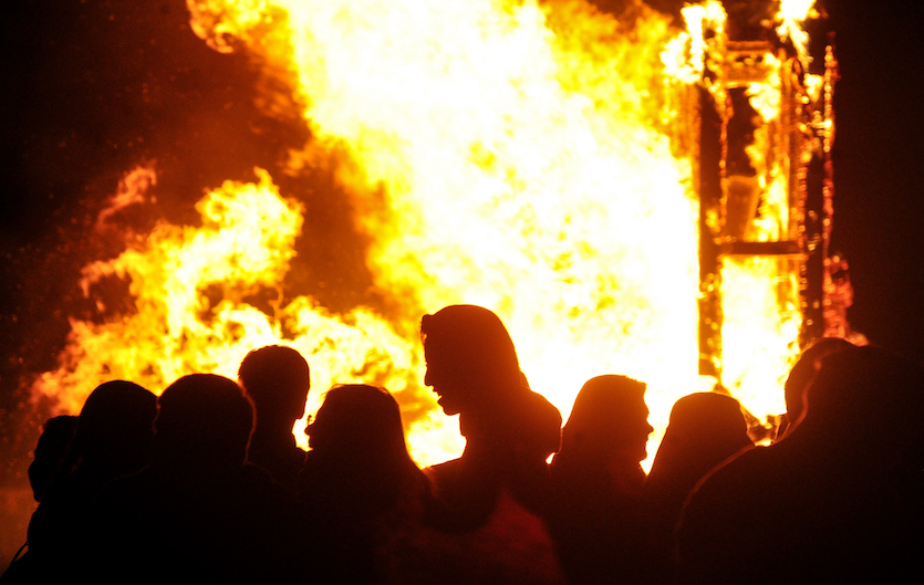 Photo of giant 2015 Homecoming bonfire with silhouette of students in the foreground.