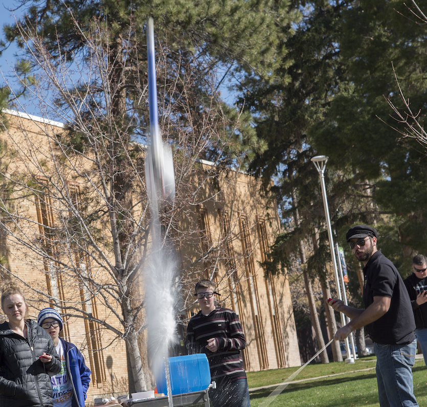 A water rocket blasting off with people watching in the background.