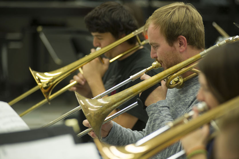 Close up photo of three trompone players. 