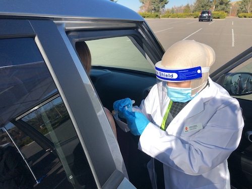 A woman gives a vaccine at a drive-through clinic