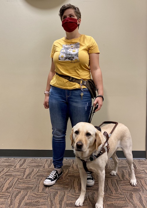 A woman stands with a service dog.