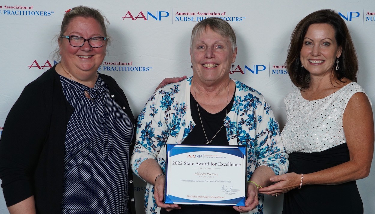 Three women hold a certificate