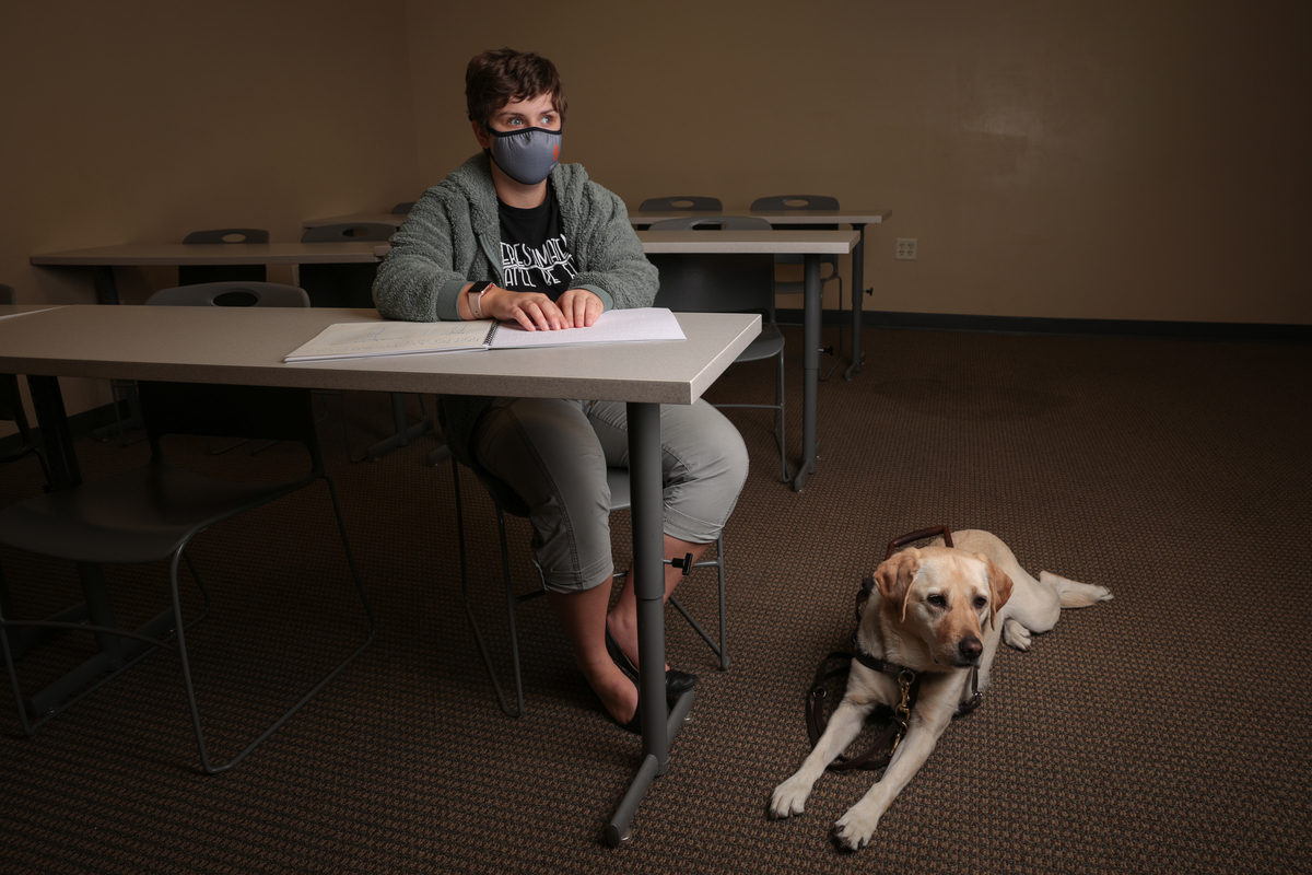 A woman sits with her service dog