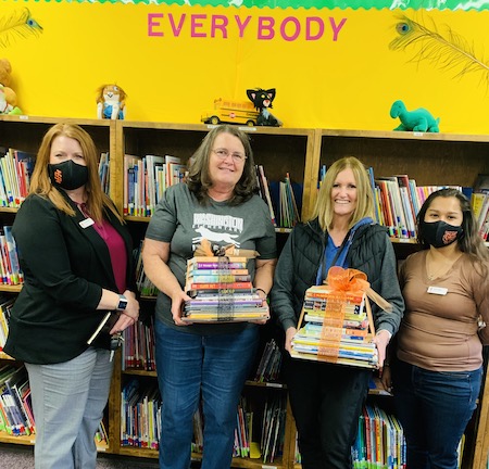 A group of four women hold books